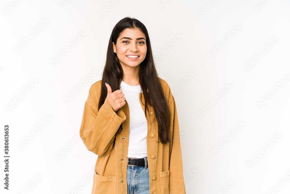 Wall mural Young indian woman isolated on purple background smiling and raising thumb up