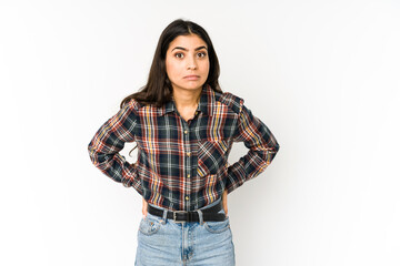 Young indian woman isolated on purple background shrugs shoulders and open eyes confused.