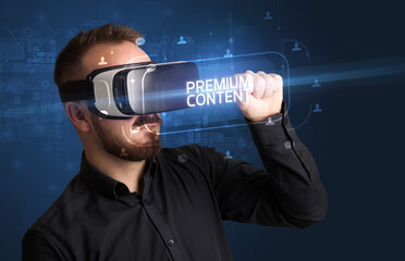 Businessman looking through Virtual Reality glasses with PREMIUM CONTENT inscription, social networking concept © ra2 studio