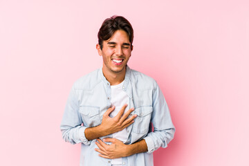 Young caucasian man posing in a pink background isolated laughs happily and has fun keeping hands...