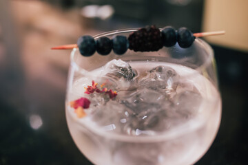 Wineglass with gin tonic decorated with berries and served with ice cubes