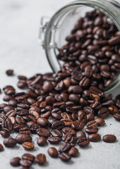 Glass jar of fresh raw organic coffee beans on light background.