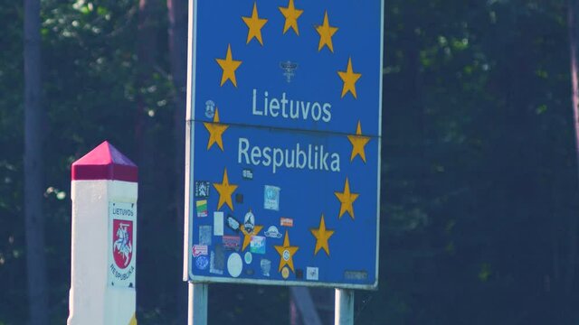 European Union border sign at the Latvia - Lithuania border, White concrete boundary stone with coat of arms of Lithuania, medium distant shot