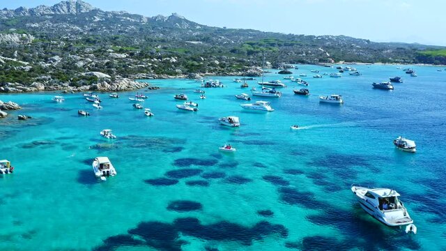 Aerial Drone View over Cala Serena at Caprera Island, Sardinia. Bay Full of Boats and Luxury Yachts. Cristal Clear Turquoise Water. Rocky Coast.