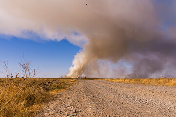 Fire in the steppe. Fire at an industrial plant. Ecological problem. Steppe road. Environmental pollution. Environmental disaster. Garbage in the steppe. Smoke screen over the plain. Dry yellow grass.