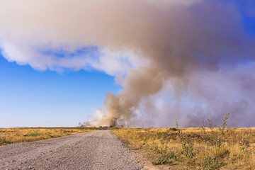 Fire in the steppe. Fire at an industrial plant. Ecological problem. Steppe road. Environmental pollution. Environmental disaster. Garbage in the steppe. Smoke screen over the plain. Dry yellow grass.