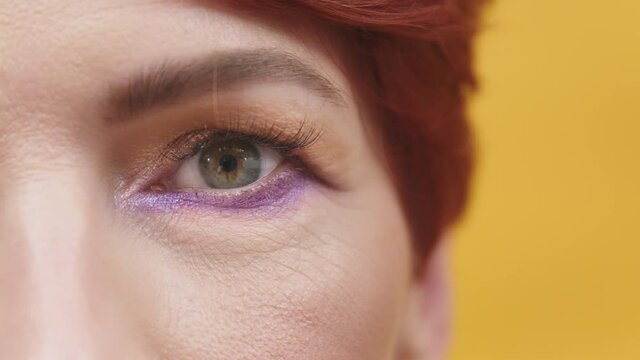Eye Of An Adult Woman Wearing A Makeup In Yellow Background. - close up shot