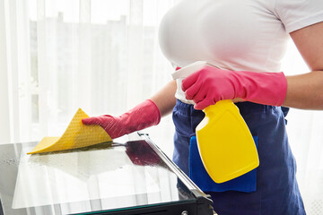 Young woman wearing gloves cleaning oven in the kitchen. Cleaning service concept