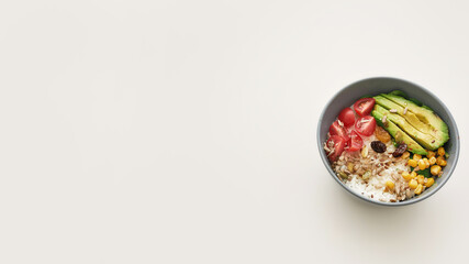 Top view of healthy vegetable bowl lunch with sliced cherry tomatoes, avocado, corn, rice and seeds isolated over white background