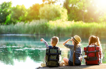 School holidays. Group of children sitting on wooden pier near river