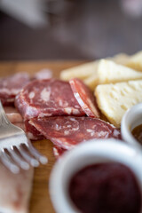 Platter of typical italian cold cuts, hams and cured meats and cheese. Salami and bacon,and a fork, the perfect italian aperitif selection. Selective focus.