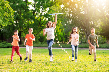 School holidays. Group of happy children playing with kite outdoors