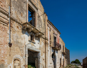 Fototapeta na wymiar Craco, Matera, Basilicata, Italy. Ghost town destroyed and abandoned following a landslide. Collapsed houses and the remains invaded by vegetation. Broken walls, windows and doors, crumbling balconies