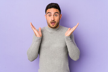 Young caucasian man isolated on purple background surprised and shocked.
