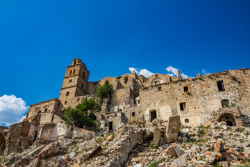 Craco, Basilicata, Italy. Ghost town destroyed and abandoned following a landslide. Collapsed houses and the remains invaded by vegetation. Broken walls, windows and doors. Bell tower of the church