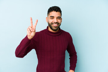 Young mixed race arabic man isolated showing victory sign and smiling broadly.