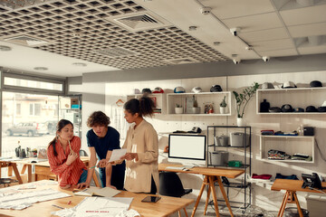 Everything you create matters. Creative people looking at notes, while discussing logo and design of T-shirt. Young man and women working together at custom T-shirt, clothing printing company