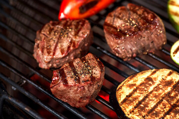 vegetables and meat sizzling on the grill with flames