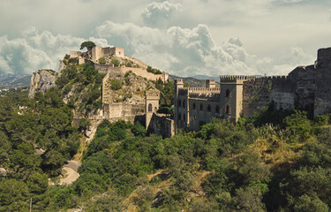 Fototapeta na wymiar Aerial image picturesque view to ancient famous castle of Xativa against cloudy sky background. Spanish landmark located on hillside top green mountain surrounding countryside. Valencia, Spain