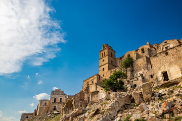Naklejka premium Craco, Basilicata, Italy. Ghost town destroyed and abandoned following a landslide. Collapsed houses and the remains invaded by vegetation. Broken walls, windows and doors. Bell tower of the church