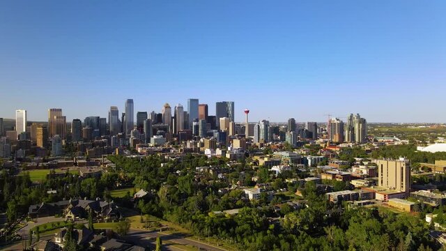 Aerial view over a park, towards skyscrapers in Downtown Calgary, during golden hour, in Alberta, Canada - Tracking, drone shot