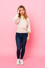 Young blonde caucasian woman standing over a pink background being shocked, she has remembered important meeting.