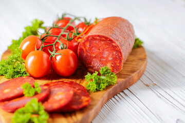 Chorizo sausage. Spanish traditional chorizo sausage with fresh tomatoes.  Served on an olive plate.