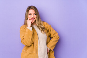 Young caucasian woman isolated on purple background relaxed thinking about something looking at a copy space.