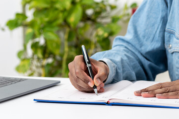 Close up of man hand writing in an agenda at home or office