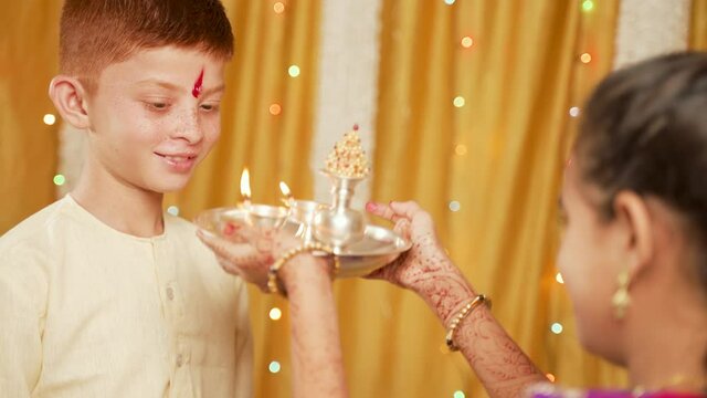 Shoulder shot, Sister offering aarati to Brother during Bhai Dooj or Bhaubeej Indian religious festival ceremony