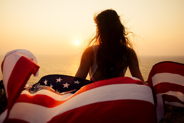woman holding USA flag and looking at sunrice
