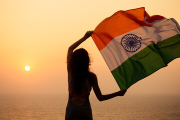 woman hjlding indian flag and looking at sunset