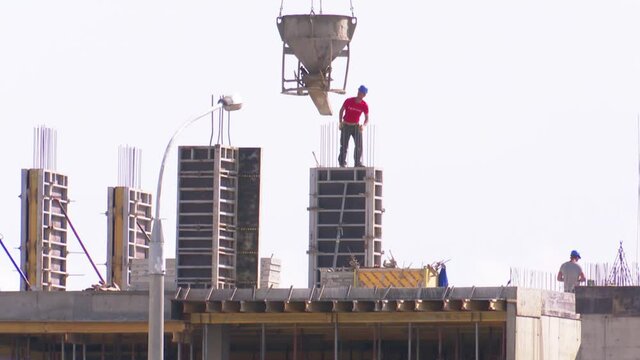 Builders on the construction site erect a monolithic building, reinforced concrete and the implementation of a variety of architectural forms.