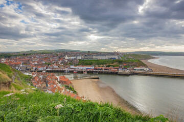 View of Whitby beach town in England with beautiful red roofs in a cloudy day.