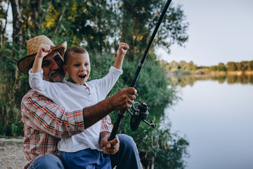 boy fishing with his grandfather outdoors at the lake