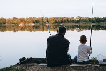 boy fishing with his grandfather outdoors at the lake