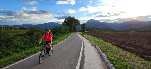 Fototapeta premium woman biking in a road with nice landscape