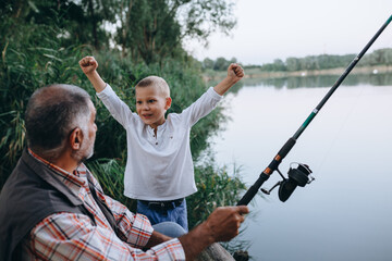 boy fishing with his grandfather outdoors at the lake