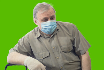 Portrait of tired and sad man in shirt and medical mask looking down and to the side, isolated on green screen background
