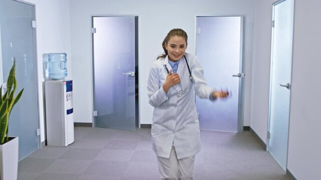 Excited doctors and nurses with a large smile dancing in front of the camera in a hospital corridor they feeling very happy