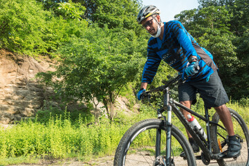 Fototapeta premium Sporty man riding a mountain bike on a forest trail