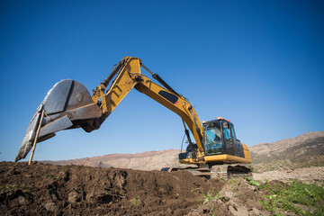 Close up wide angle image of an excavator machine working on an agricultural farm