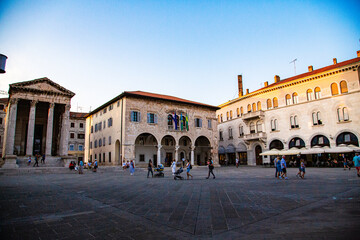 Plaza mayor with town hall and mausoleum with people walking