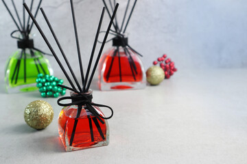 beautiful Christmas design aroma scented reed diffuser glass bottles are displayed on the grey table with Christmas ornaments and cement wall background during Christmas celebration festival new year
