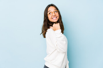 Young mixed race hispanic woman isolated points with thumb finger away, laughing and carefree.