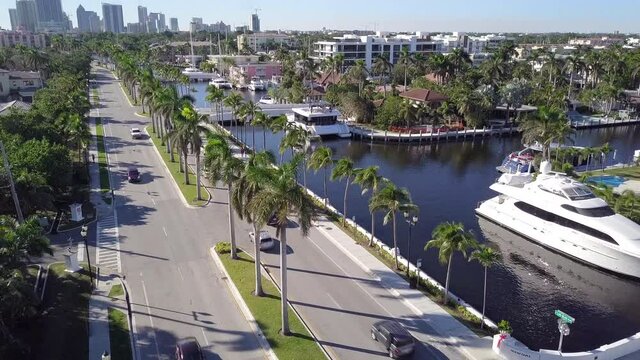 Cinematic aerial drone jib down in Luxury neighborhood, cars drive by en high buildings in the background