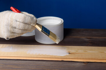 A can of white paint and a paintbrush on a wooden table