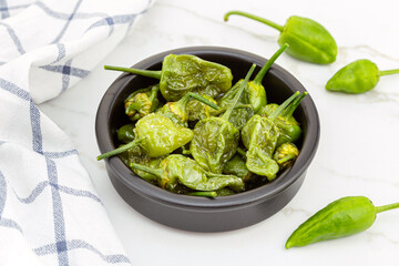 Cooked Padron peppers in a a bowl on marble table. Traditional Spanish appetizer