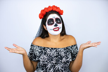 Woman wearing day of the dead costume over isolated white background clueless and confused expression with arms and hands raised