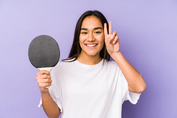 Young indian woman playing ping pong isolated showing victory sign and smiling broadly.